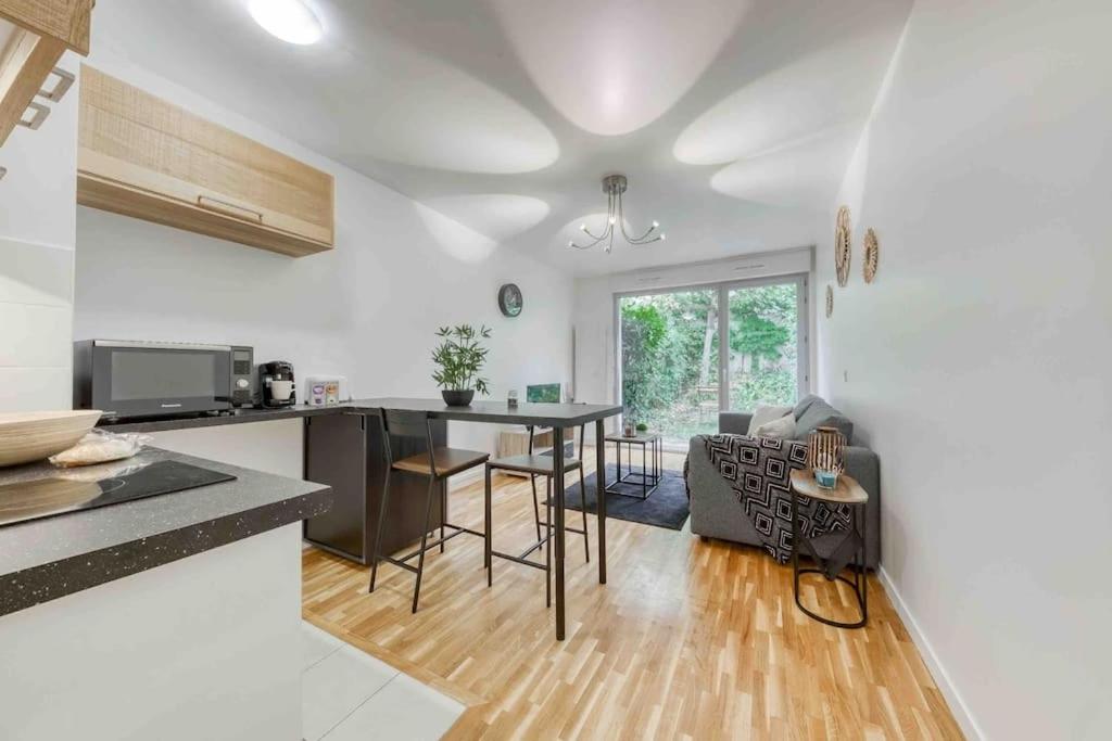 Una cocina y una sala de estar con mesa y sillas. en Appartement moderne, Metro 7, Parking et Jardin, en Villejuif