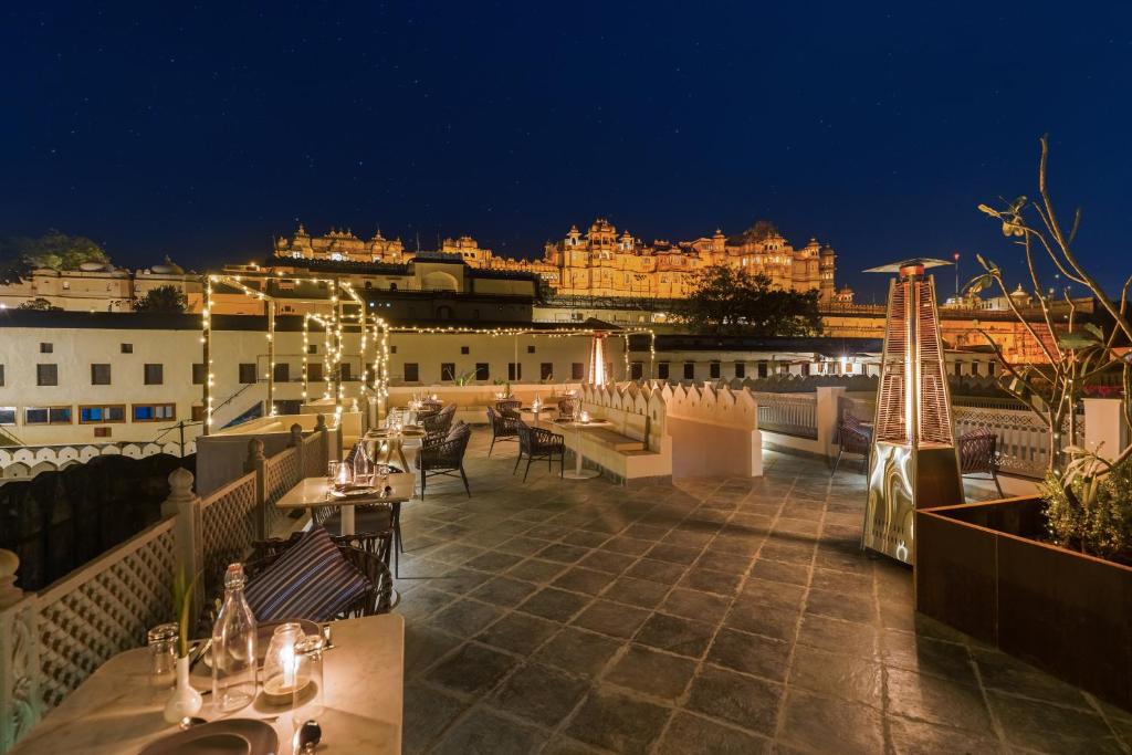 a rooftop restaurant with a view of the city at night at Manuscript - Jhilwara Haveli in Udaipur