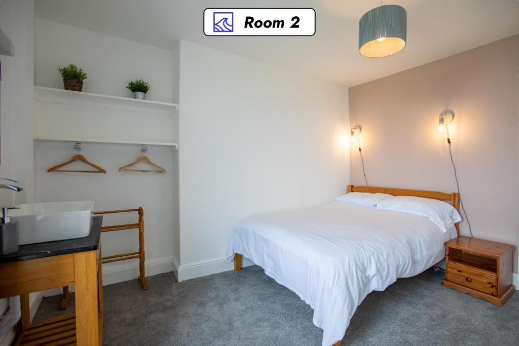 a bedroom with a bed and a desk and a sink at OA Surf Club in Bude