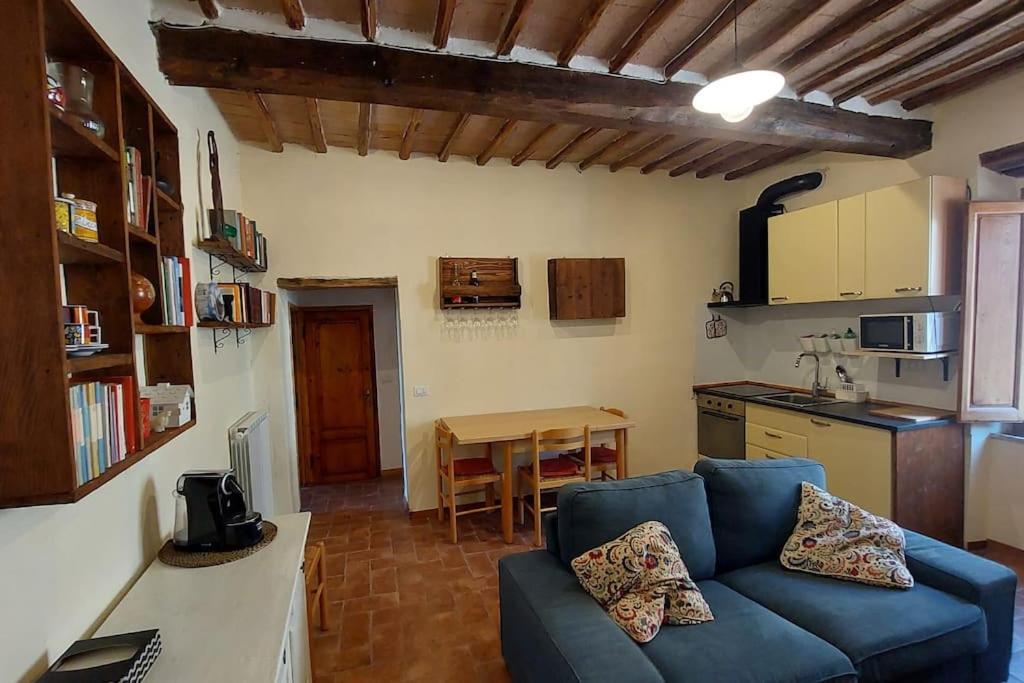 ein Wohnzimmer mit einem blauen Sofa und einer Küche in der Unterkunft piccolo appartamento in Monticiano