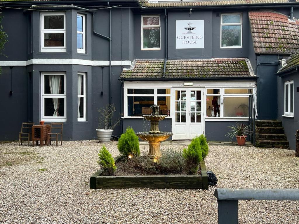 a blue house with a fountain in front of it at Guestling House in Guestling