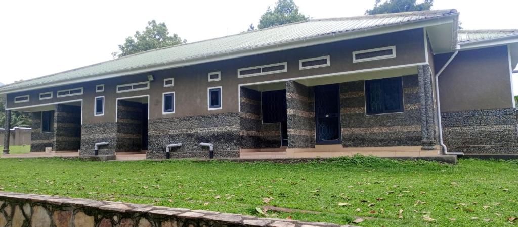 ein großes Backsteingebäude mit einem Rasenplatz davor in der Unterkunft Rwenzori Base camp tour Holiday Inn in Kasese