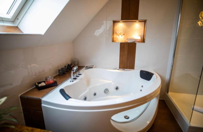 uma grande banheira branca na casa de banho com uma janela em Vier Jahreszeiten Suite mit Whirlpool Badewanne L Vazzano em Husum