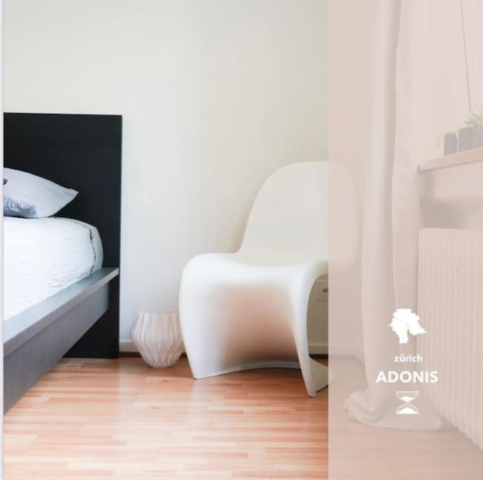 ein Schlafzimmer mit einem Bett und einem weißen Stuhl in der Unterkunft Wohnen in Wiedikon Adonis in Zürich