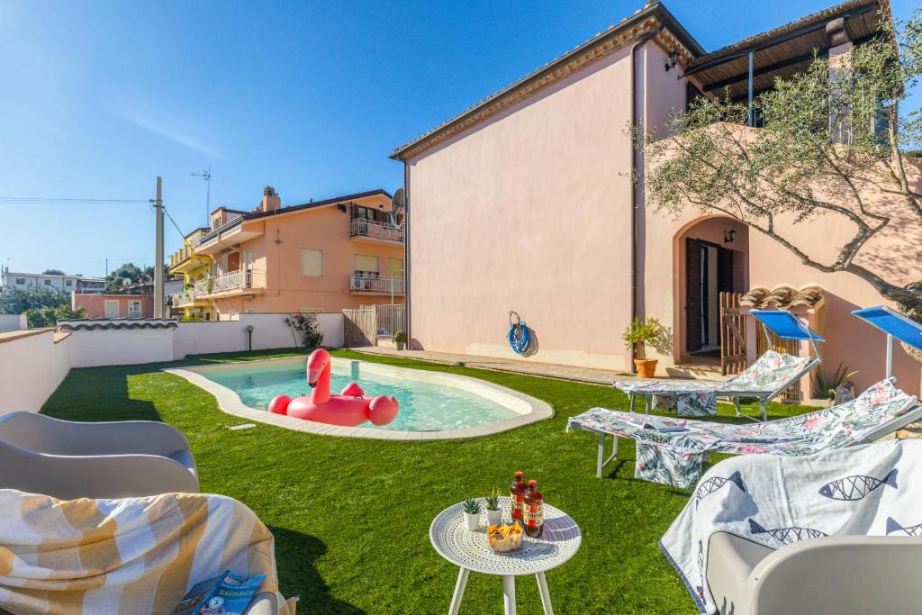 a backyard with a pool with chairs and a table at ByNos Pool - Primo Piano in Santa Maria Navarrese