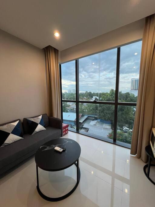 a living room with a couch and a table and a large window at Kozi Square Dual Unit (1 bedroom, 1 living room) in Kuching