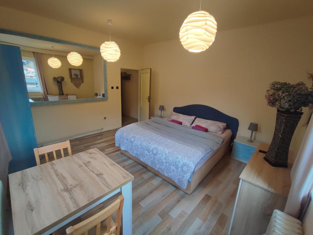 1 dormitorio con cama, mesa y luces colgantes en Penzion Přívoz en Hřensko