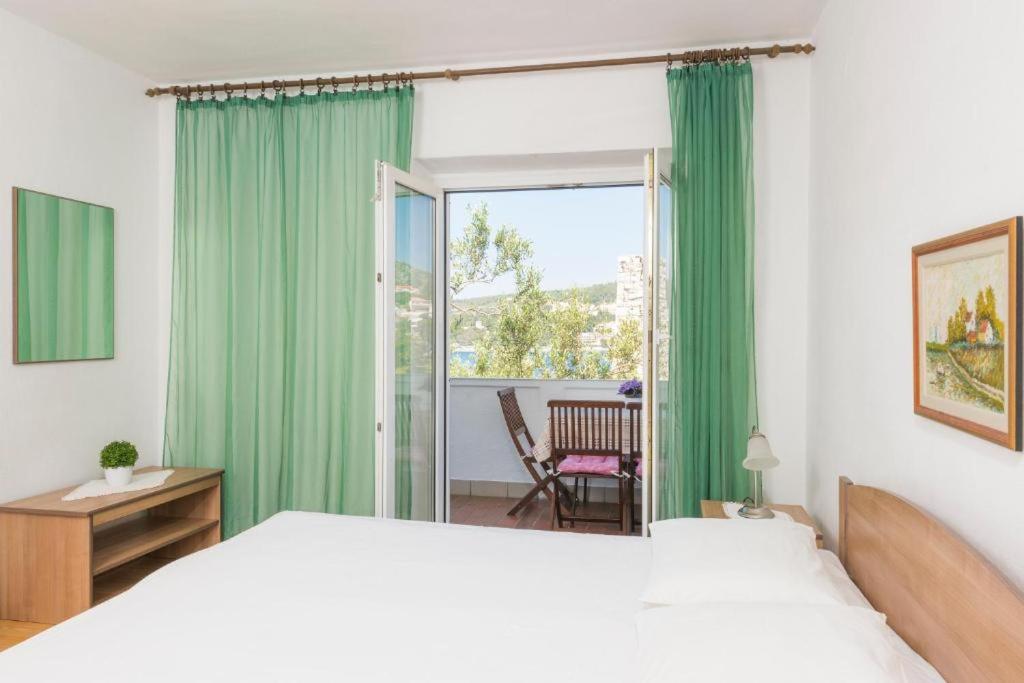 1 dormitorio con 1 cama y una ventana con cortinas verdes en Sunset house with seaview en Hvar