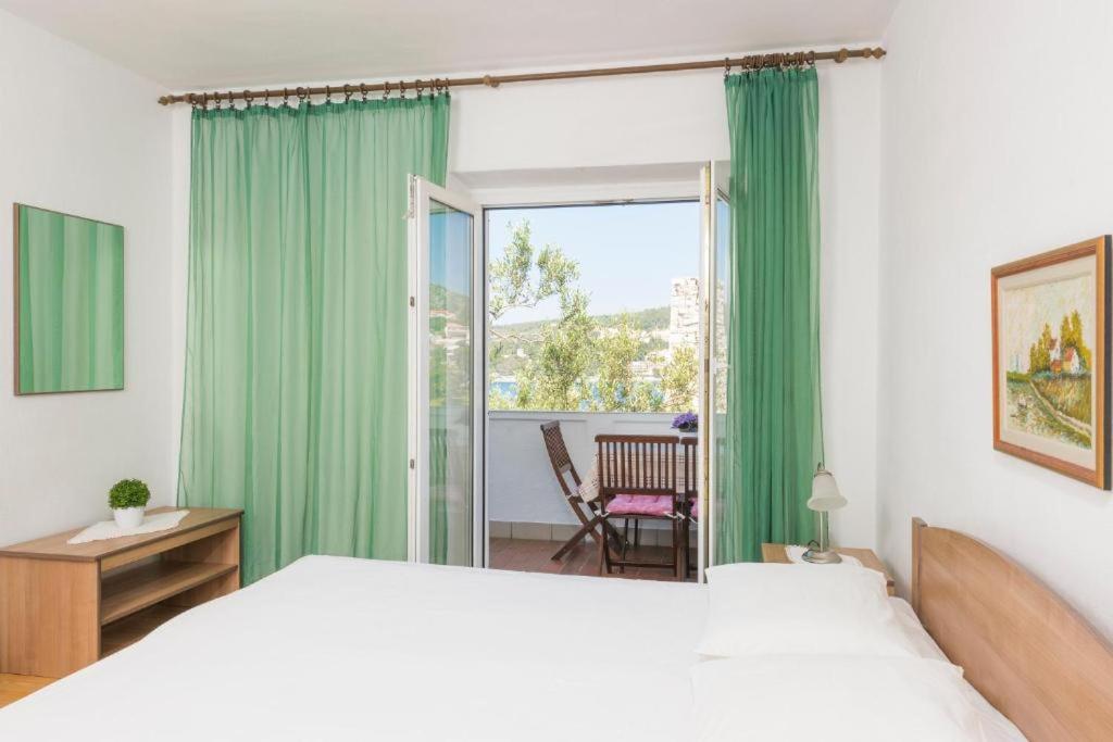 1 dormitorio con 1 cama y una ventana con cortinas verdes en Sunset house with seaview, en Hvar