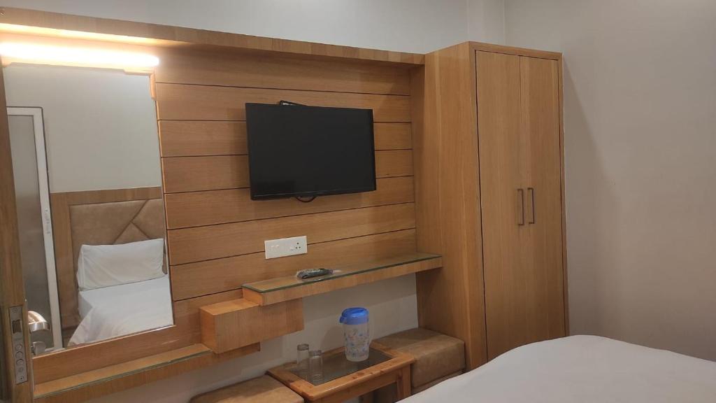ein Schlafzimmer mit einem TV an einer Holzwand in der Unterkunft HOTEL GANGARANI in Haridwar