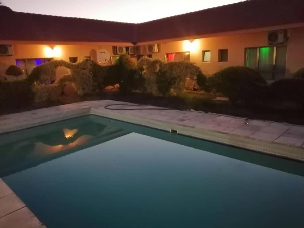 a swimming pool in front of a house at night at Okavango Roadside Guesthouse in Maun