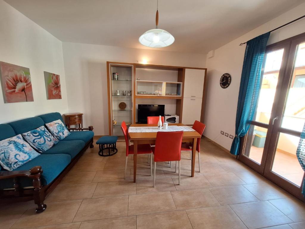 ein Wohnzimmer mit einem blauen Sofa, einem Tisch und Stühlen in der Unterkunft Casa di Lu in SantʼAntìoco