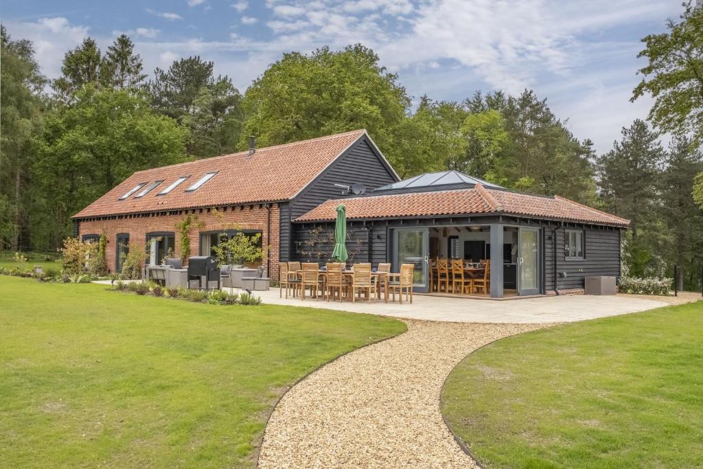 a building with a table and chairs in a yard at Wild Meadow Barn in Aylsham