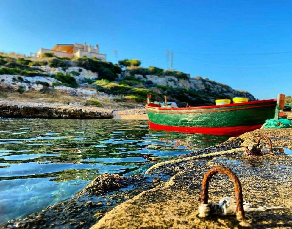 a boat sitting on the shore of a body of water at Villa Incina - Sea House in Polignano a Mare