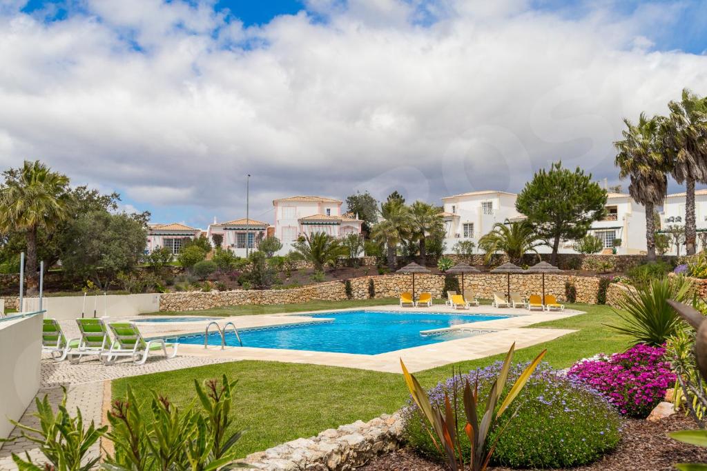 a pool in a yard with chairs and plants at Quinta do Rosal, Casa Rosa in Carvoeiro