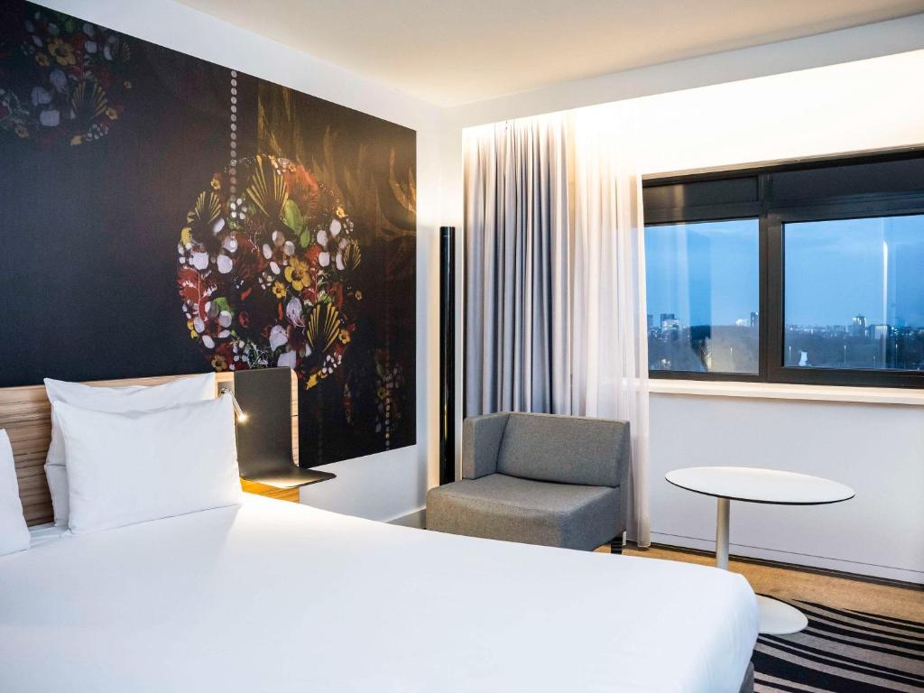 a hotel room with a bed and a chair at Novotel Amsterdam City in Amsterdam