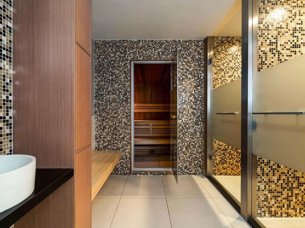 a bathroom with a shower and a tub and a sink at Novotel Amsterdam City in Amsterdam