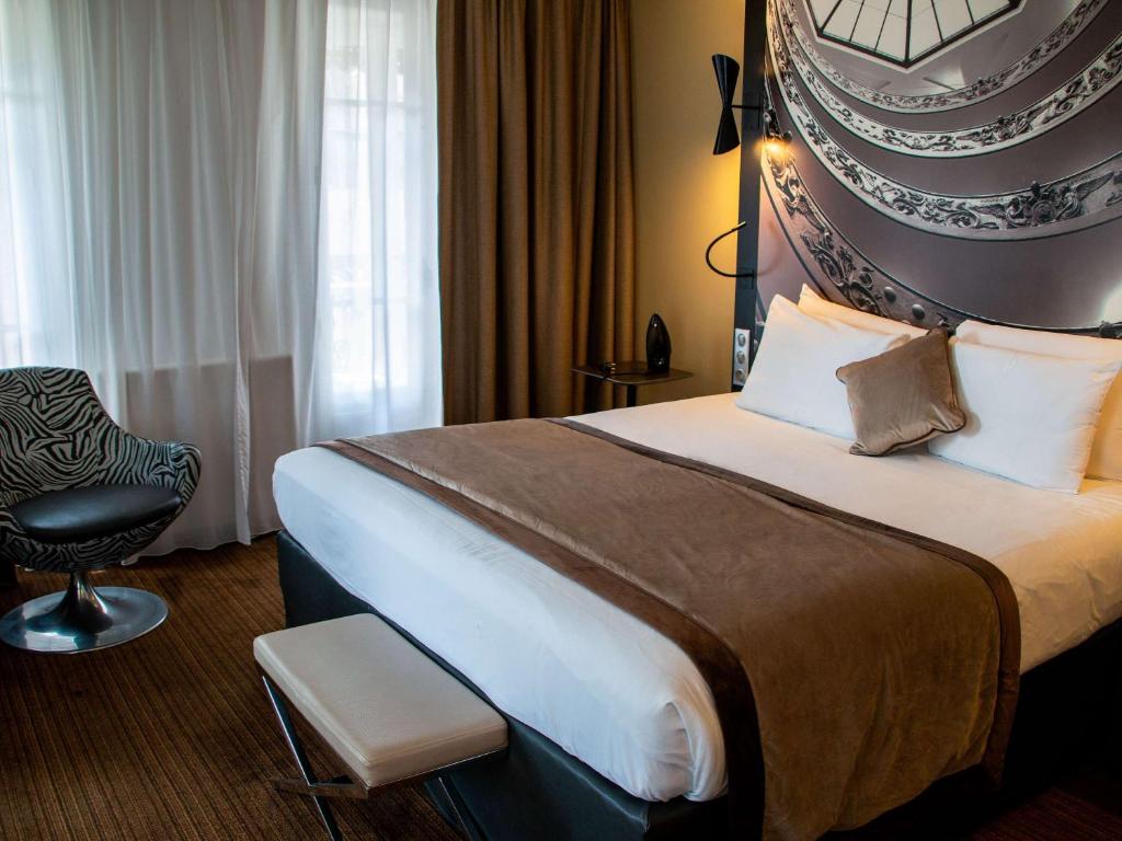 a hotel room with a large bed and a chair at Mercure Lyon Centre Beaux-Arts in Lyon