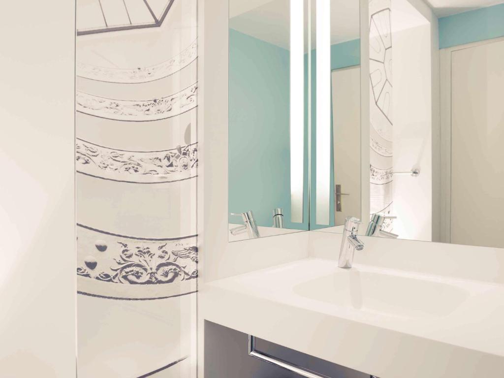 a bathroom with a sink and a mirror at Mercure Lyon Centre Beaux-Arts in Lyon