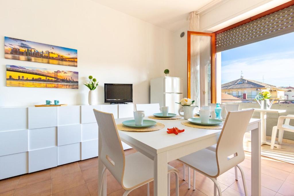 un comedor blanco con una mesa y sillas blancas en Appartamento Alba Rosa 3 - MyHo Casa, en Alba Adriatica