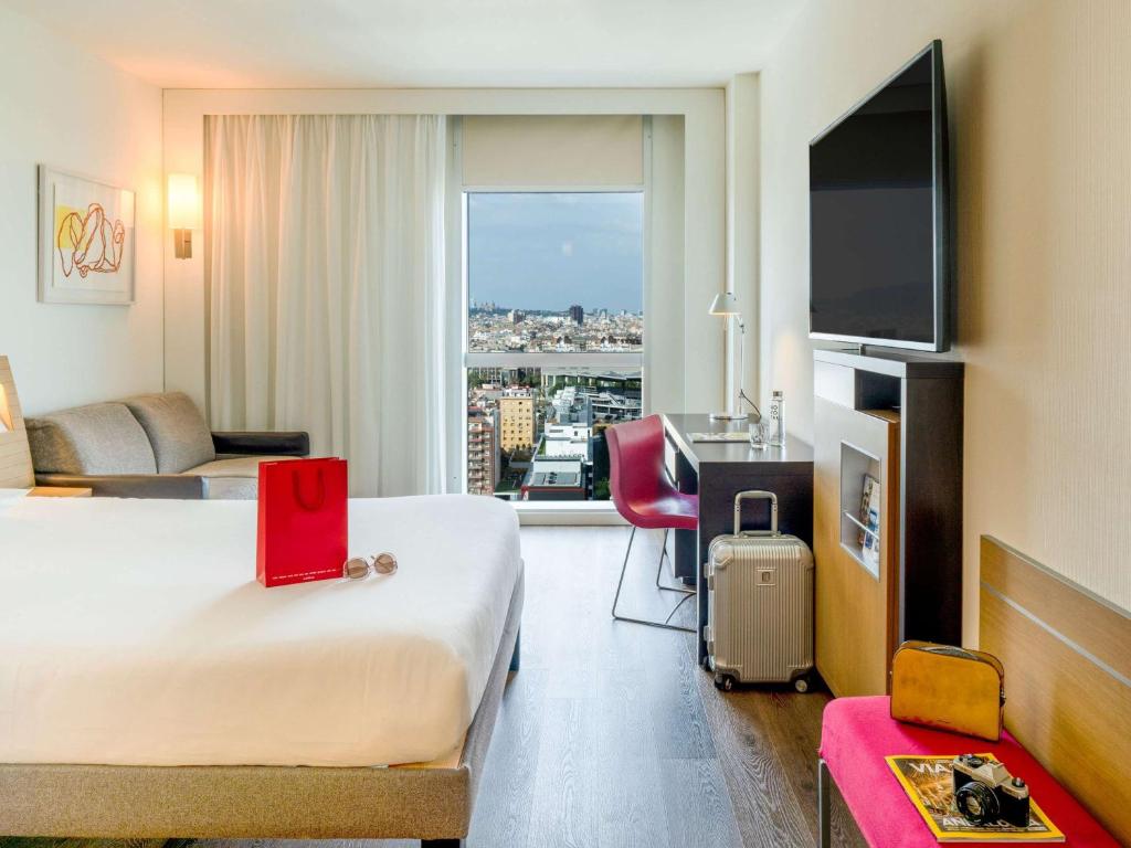 a hotel room with a bed and a large window at Novotel Barcelona City in Barcelona