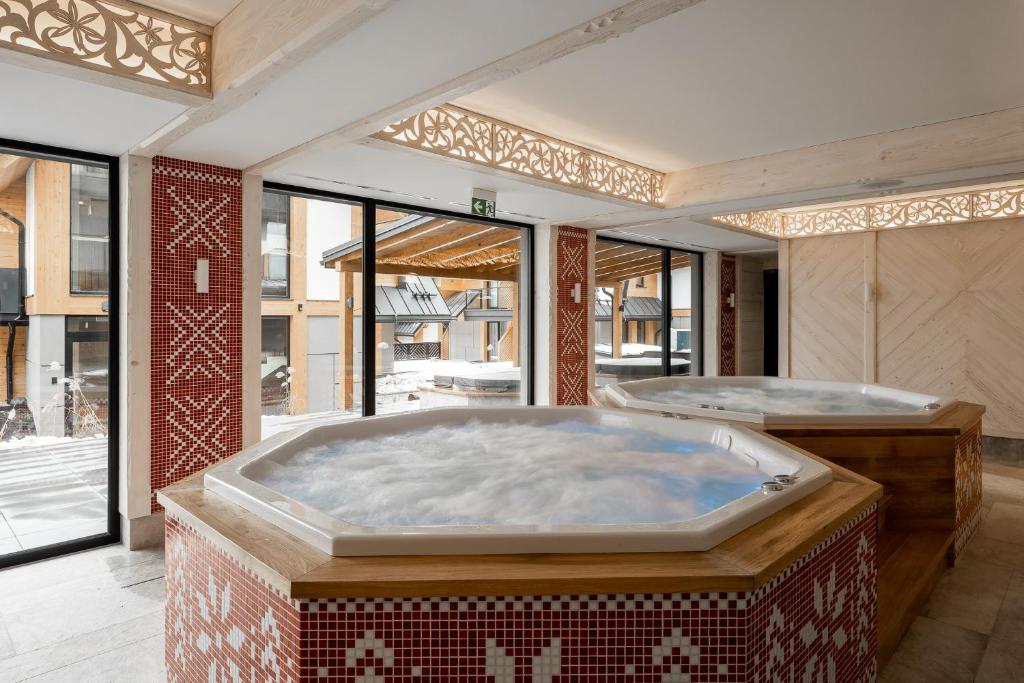 a large jacuzzi tub in a room with windows at Apartamenty Aries Residence Bukowina in Bukowina Tatrzańska