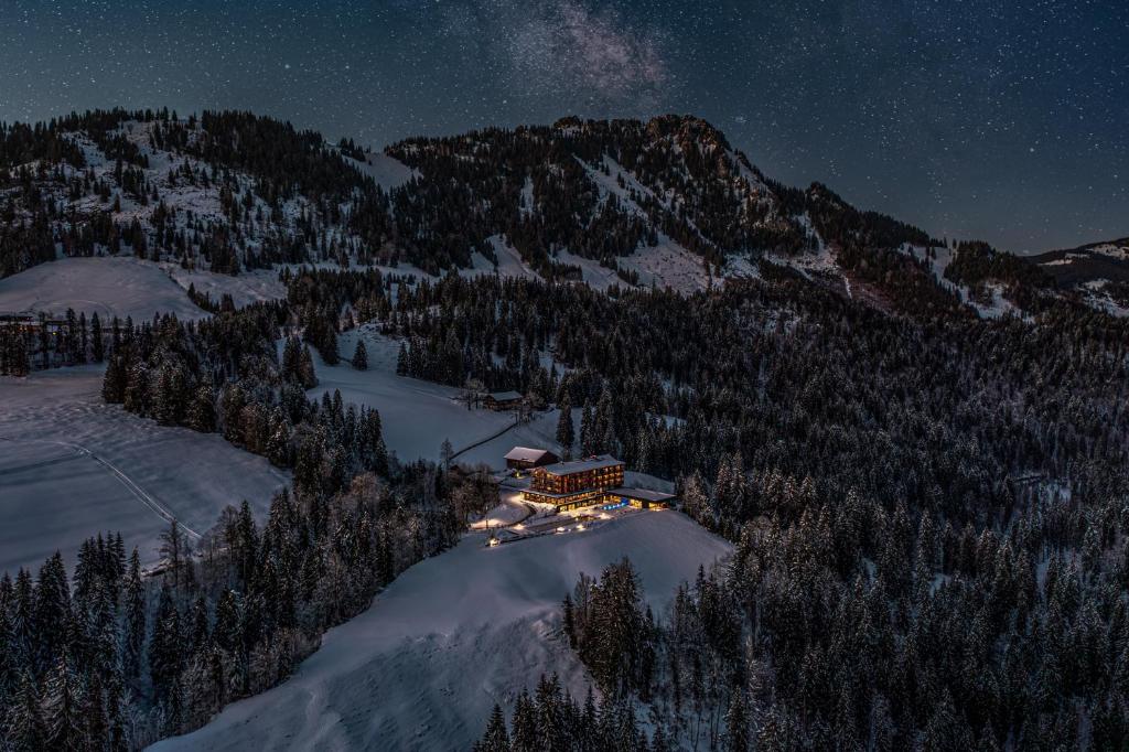 a building on a mountain at night in the snow at Ruhehotel & Naturresort Rehbach - Adults only in Schattwald