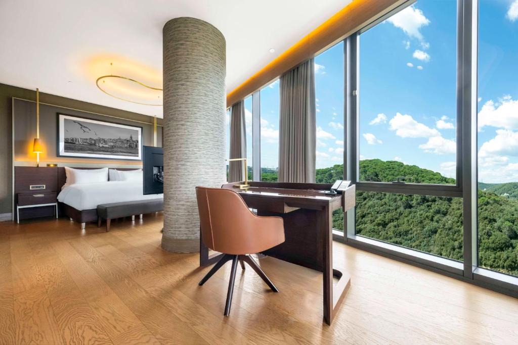 a hotel room with a desk and a bed and windows at Radisson Collection Hotel, Vadistanbul in Istanbul