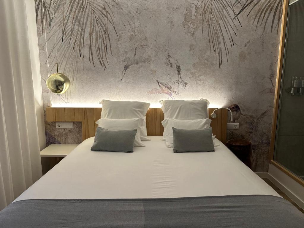 1 cama con sábanas blancas y almohadas en una habitación en Charm-In Center en Vila Nova de Milfontes