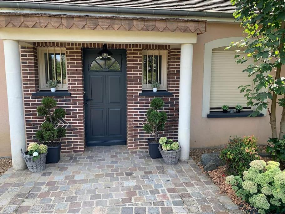 a brick house with a black door and potted plants at Gite de Groupe Aux Instants Partagés in Fontenay-sur-Vègre