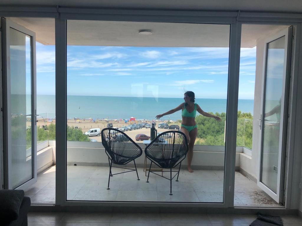Eine Frau steht auf einem Balkon mit Meerblick in der Unterkunft Carpe Diem Monte Hermoso in Monte Hermoso