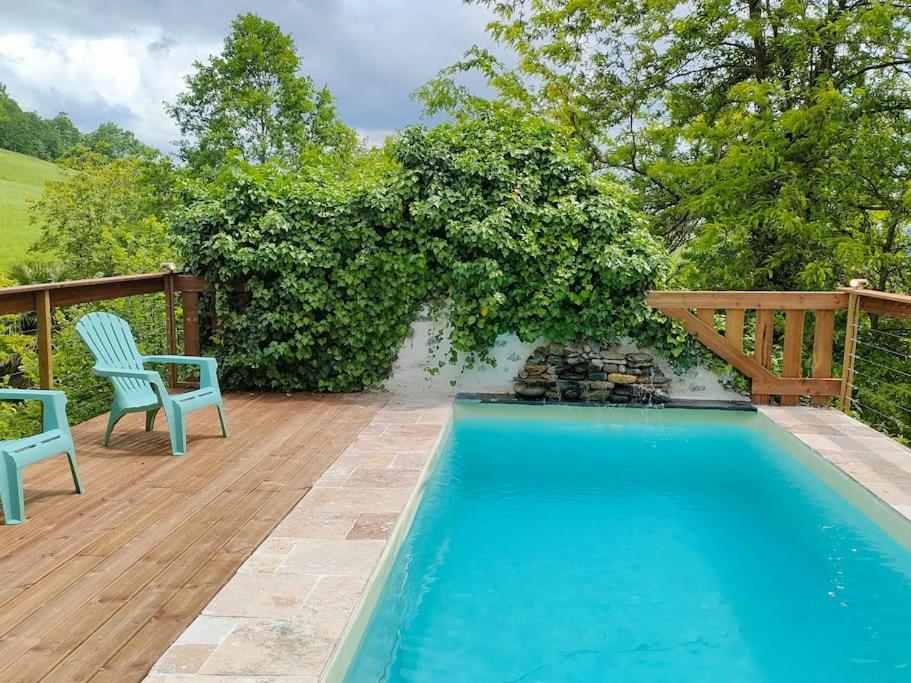 une piscine avec deux chaises bleues et une terrasse en bois dans l'établissement paradis perdu piscine jacuzzi billard baby-foot, à Louvie-Juzon