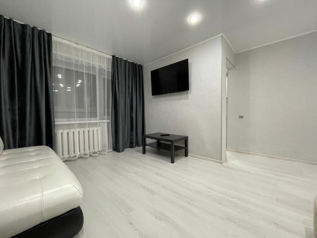 a white room with a bed and a television at 1-комнатная квартира с дизайнерским ремонтов в районе Вокзала in Petropavlovsk