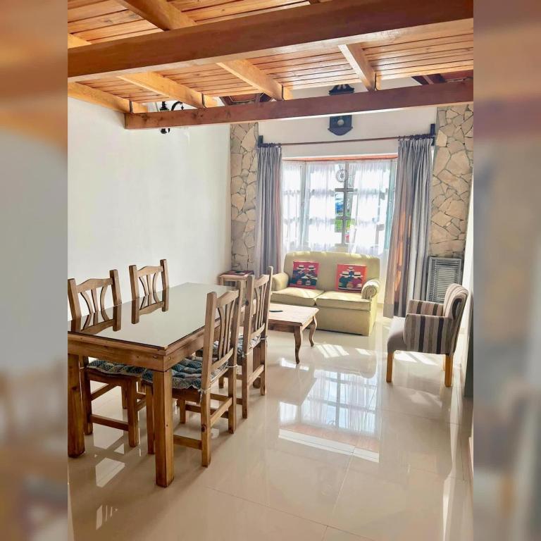 een woonkamer met een tafel, stoelen en een bank bij Zorzal Tempo in Esquel