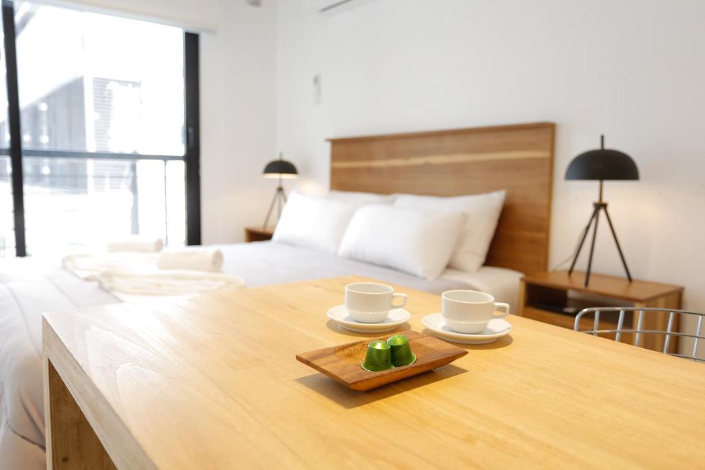 Un dormitorio con una cama y una mesa de madera con tazas y platos. en OWN Belgrano Studios & Suites en Buenos Aires