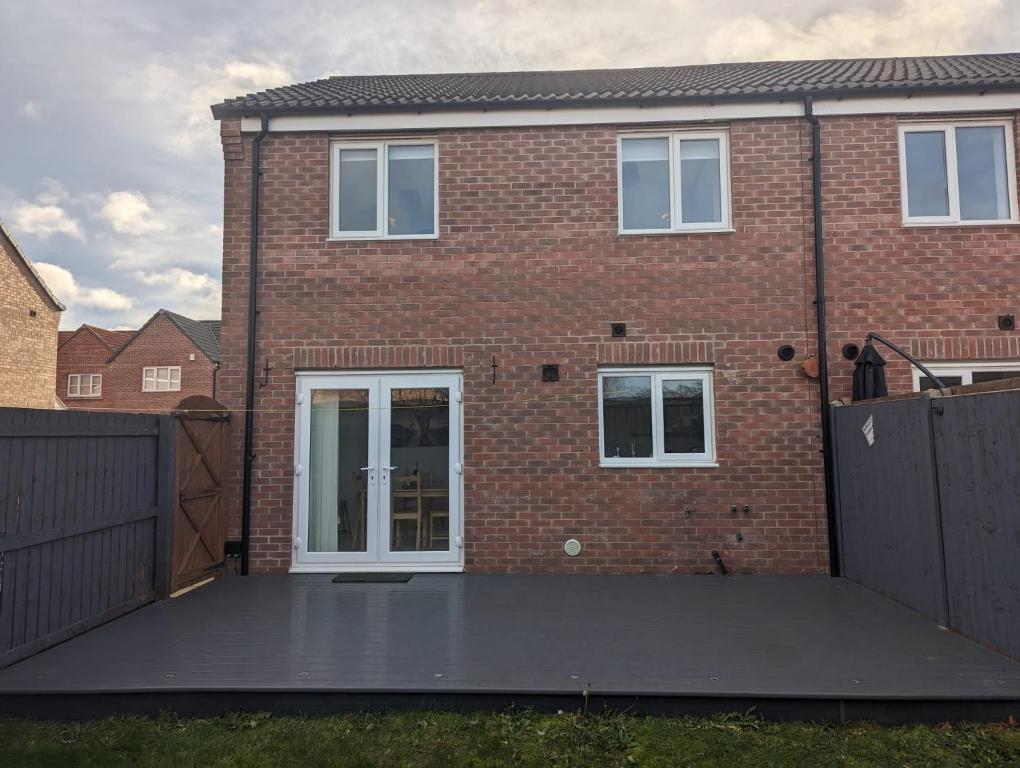 une maison en briques avec une grande terrasse en face de celle-ci dans l'établissement Freshen-up stays Doncaster, à Bentley