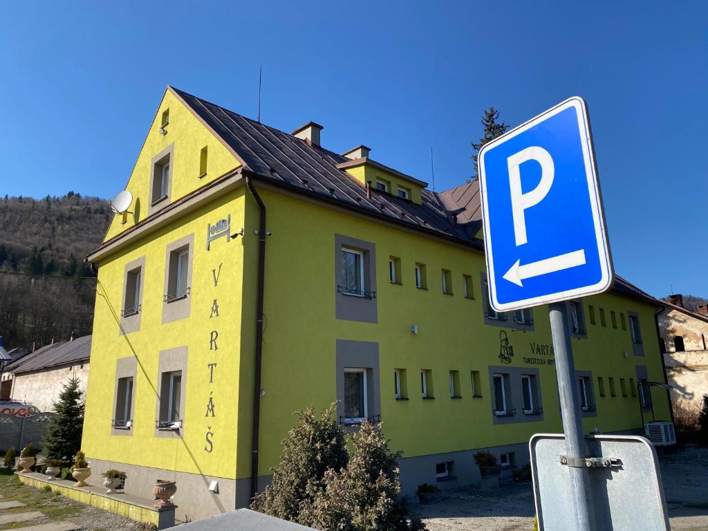 a parking sign in front of a yellow building at Turistická ubytovňa Vartáš in Oravský Podzámok