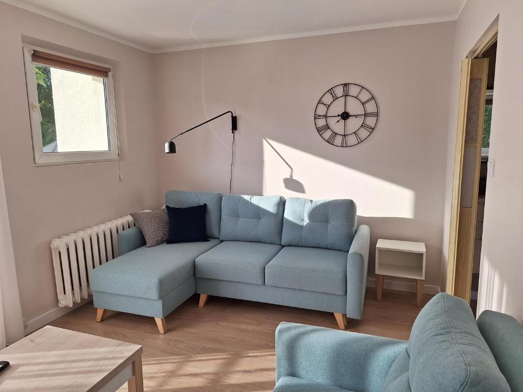 a living room with a blue couch and a clock on the wall at Apartament Kamienny Potok Sopot in Sopot