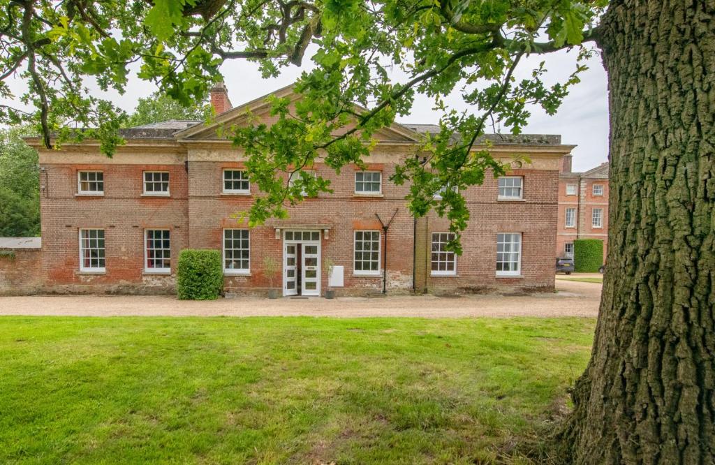 an old brick building with a tree in the foreground at East Wing Apartment in Wymondham