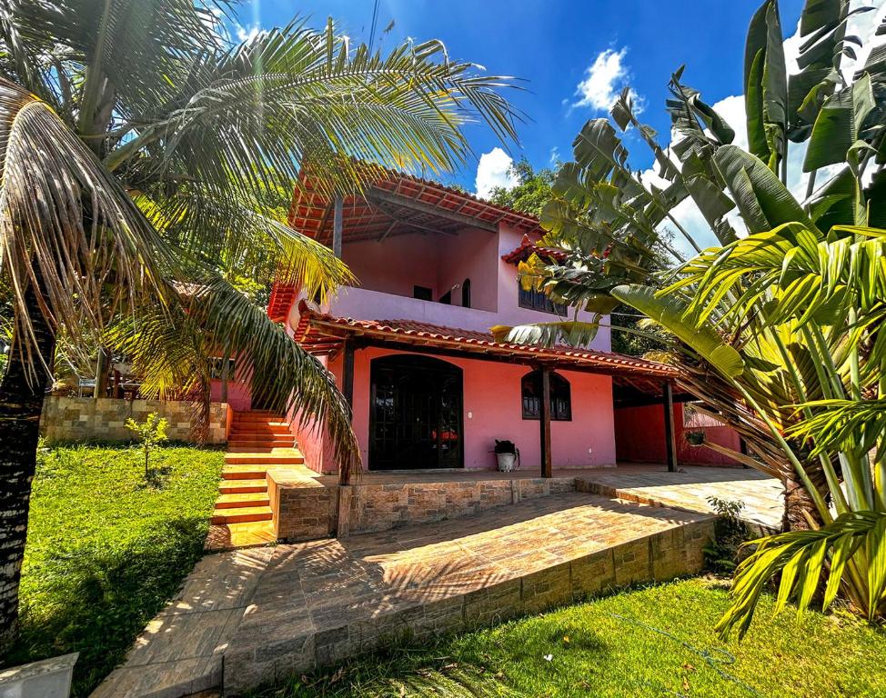 Una casa rosa con escaleras que conducen a la parte delantera. en Casa de campo c vista para a Lagoa de Saquarema RJ, en Saquarema