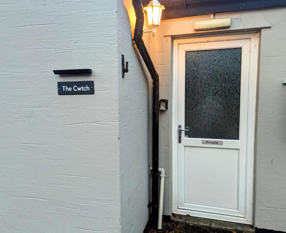 een deur met een bord waarop de agent ernaast staat bij The Cwtch Flat at The Lodge by Cefn Tilla in Usk