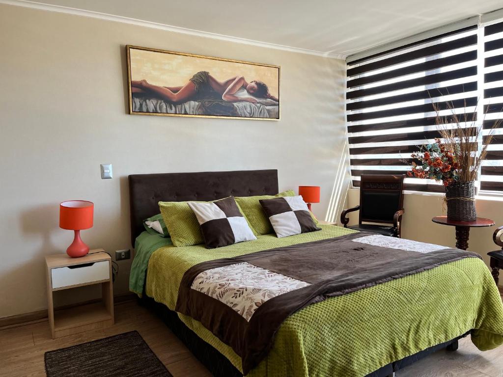 um quarto com uma cama com lençóis verdes e uma janela em Depto 1 Dormitorio Centro Blanco 702 em Temuco