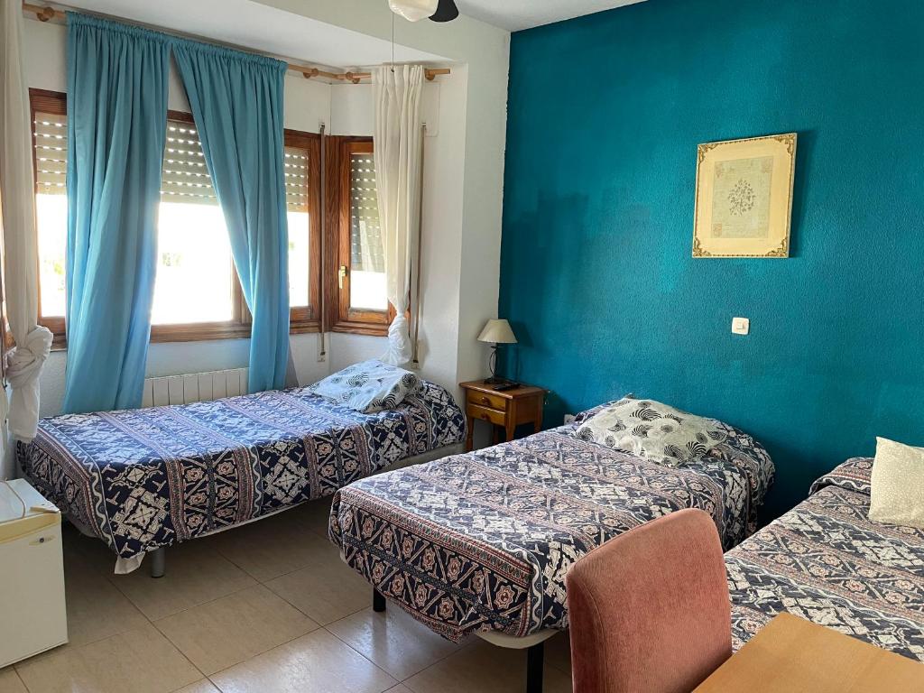 Habitación de hotel con 2 camas y paredes azules en Hostal El Alba en Brunete