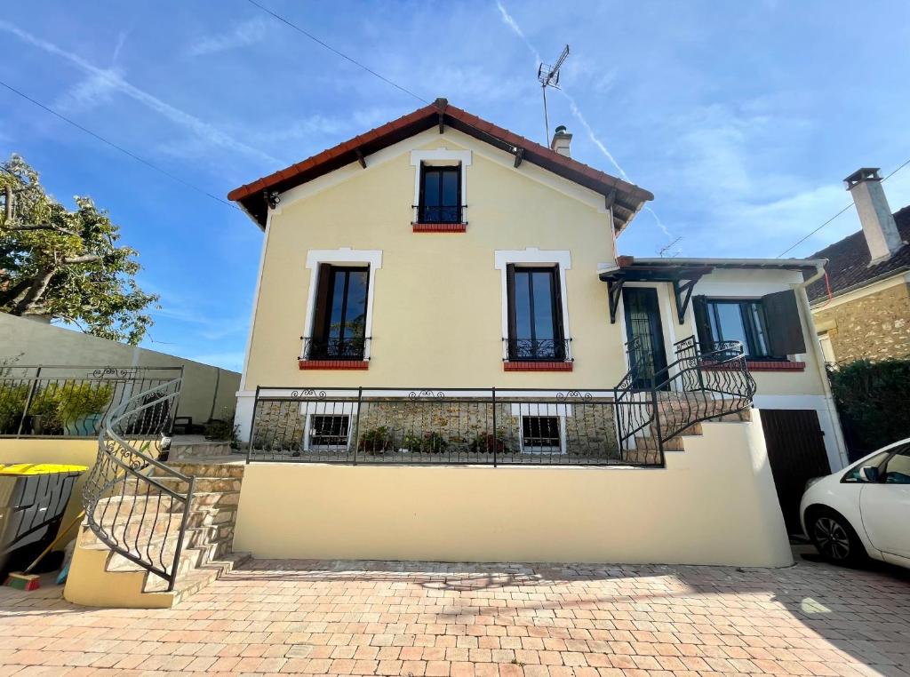 a white house with black windows on a brick driveway at En route pour disney et shopping a la vallée village in Couilly-Pont-aux-Dames