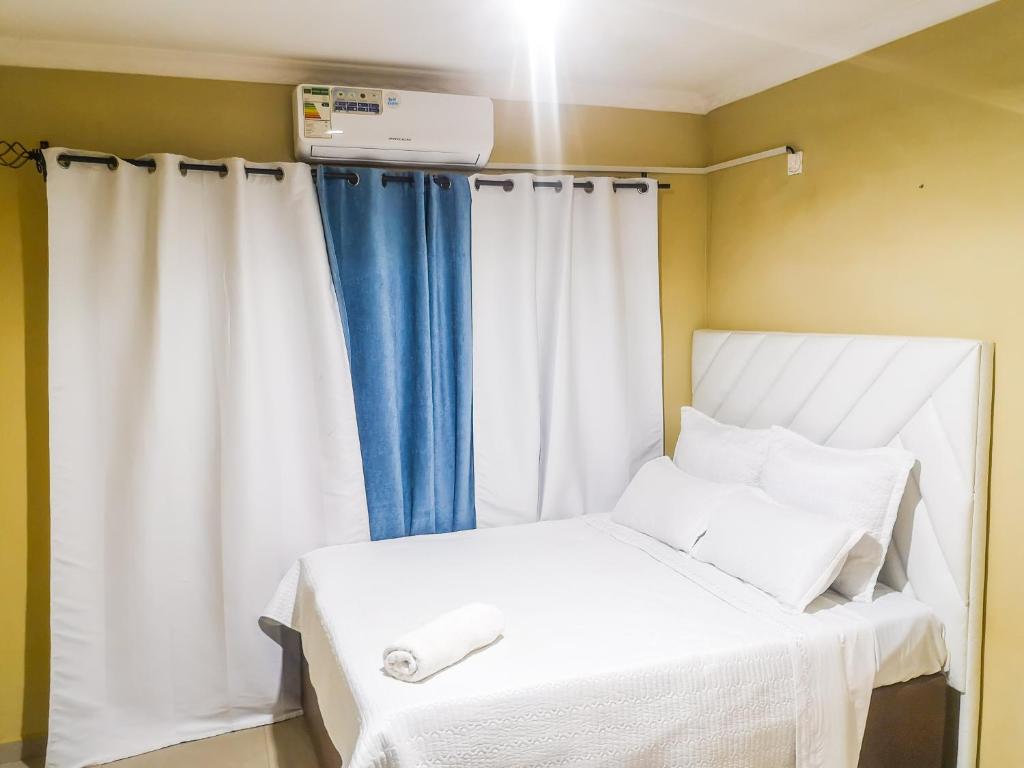 a bedroom with a white bed with a blue curtain at Wangu Apartments in Livingstone