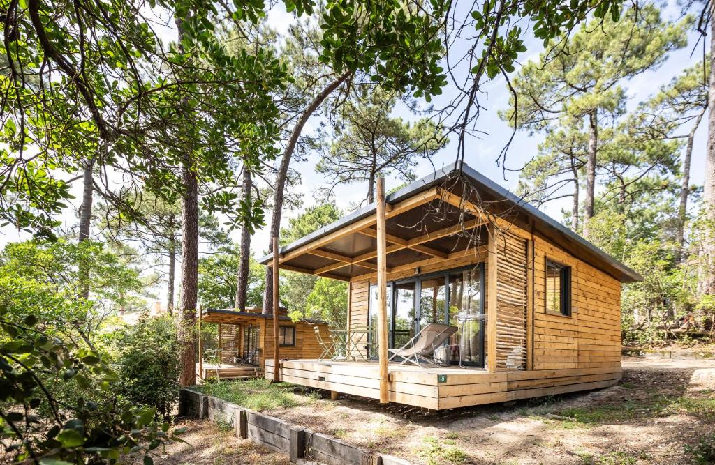una piccola cabina in legno nel bosco con alberi di Huttopia Arcachon ad Arcachon