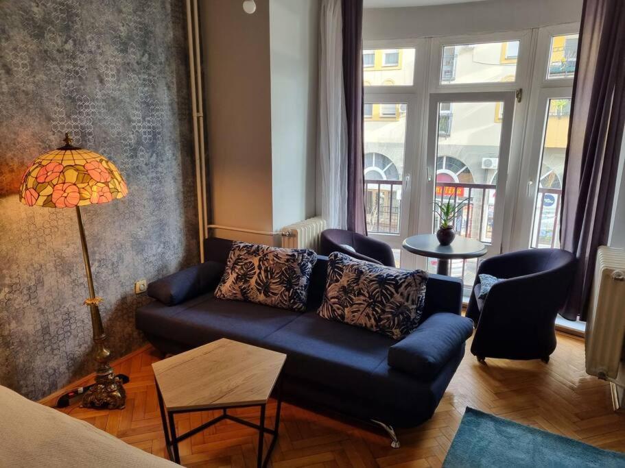 a living room with a blue couch and a lamp at Apartment Vuksa in Novi Sad