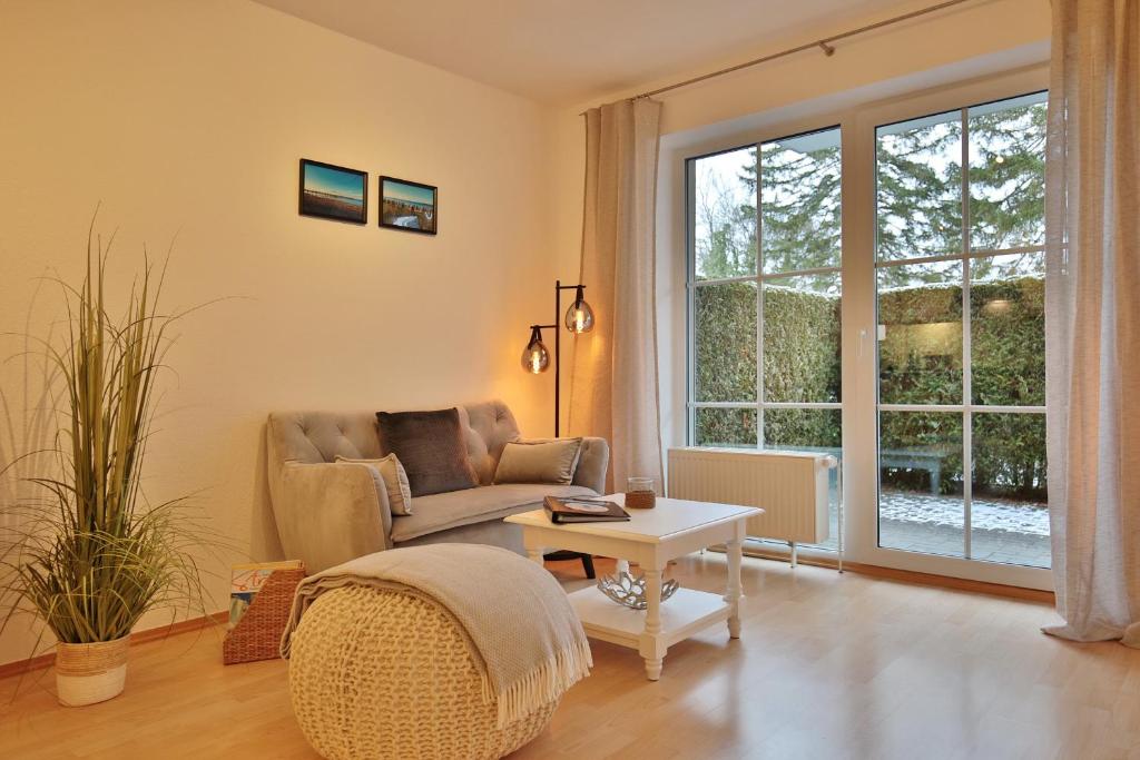 ein Wohnzimmer mit einem Stuhl, einem Tisch und einem Fenster in der Unterkunft Bädervilla Bergstraße 30 Bädervilla Bergstraße Appartement 2 in Timmendorfer Strand
