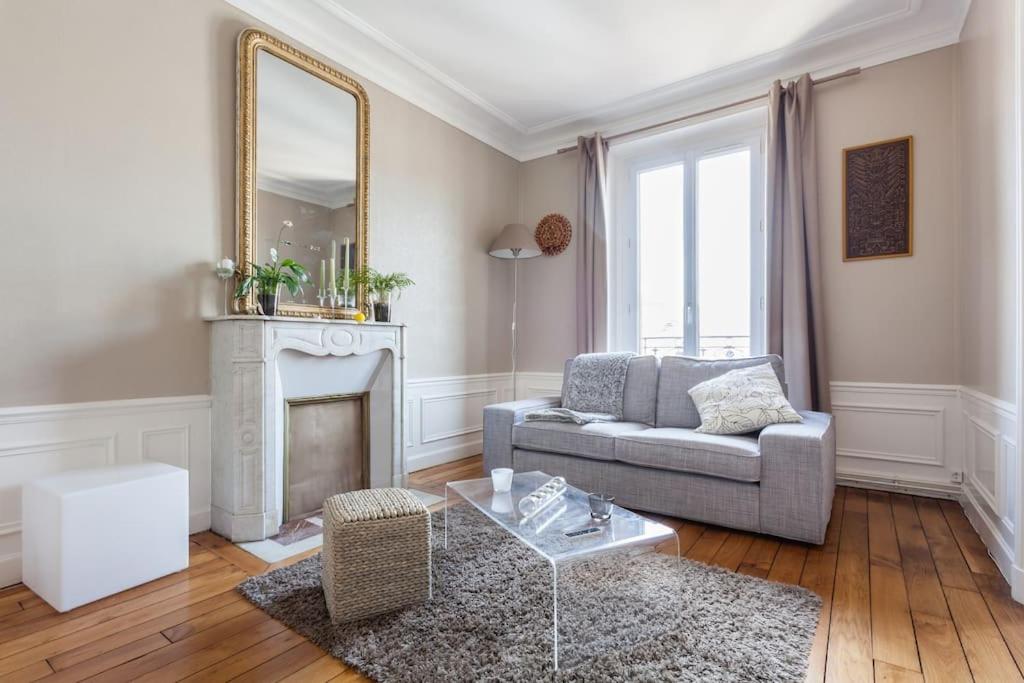 een woonkamer met een bank en een spiegel bij Appartement calme avec cachet (20 min de Paris) in Maisons-Laffitte