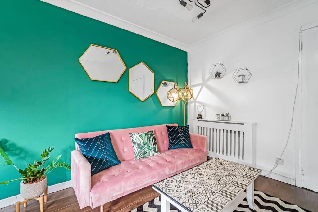 een woonkamer met een roze bank en een groene muur bij BrightCentral Apartment With Parking in Glasgow